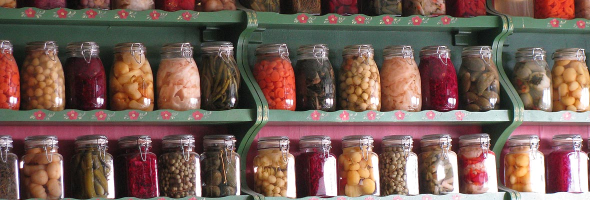 Das Bild zeigt Regale voller Einmachgläser mit vielen verschiedenen eingelegten Gemüsesorten.