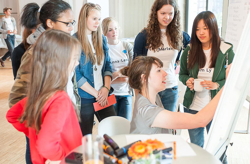 The young people compile ideas, one girl makes a note.